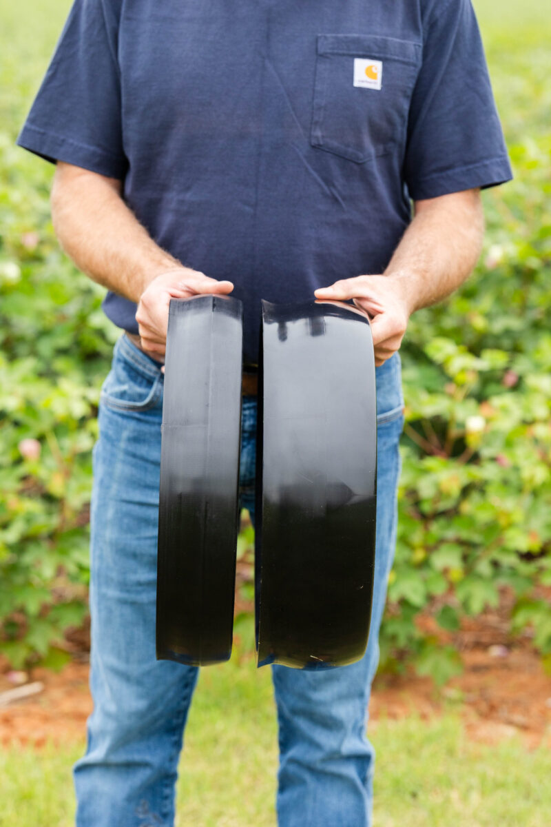 Farmer holding planter gauge wheel components for no-till planting.