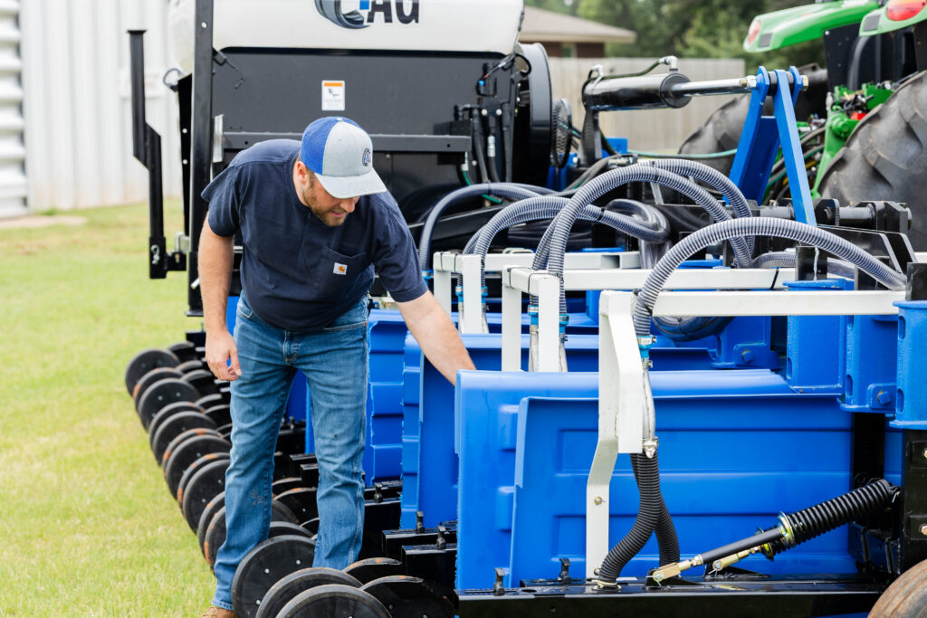 Farmer inspecting 4AG interseeder no-till equipment seeder machine in the field as an alternative to a no till seed drill for cover crop integration.