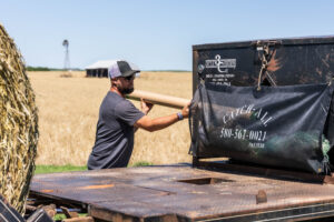 Oklahoma farmer placing net wrap into Catch All on flatbeds to keep net wrap secure during feeding operations