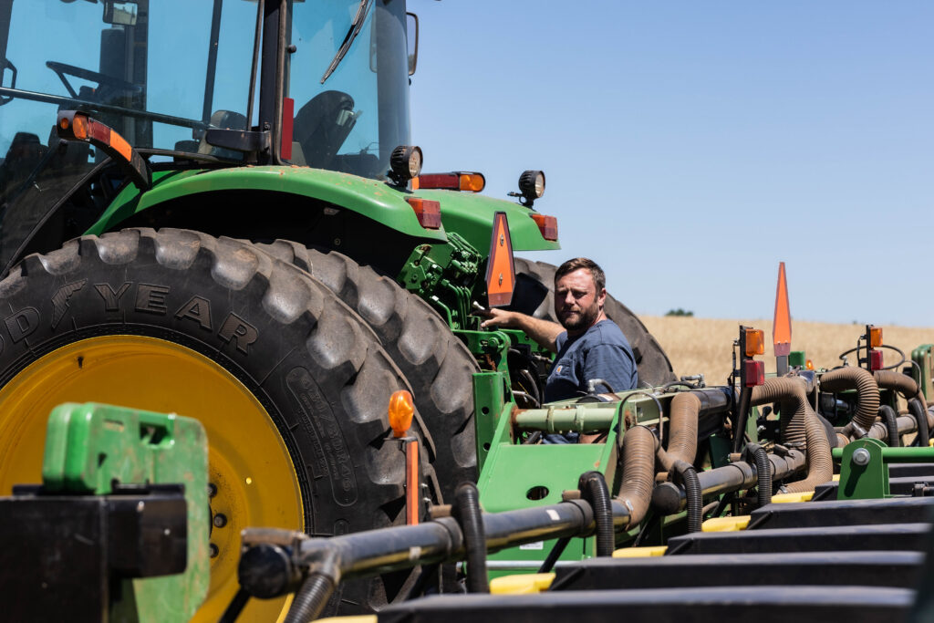 Farmer operating tractor with no till equipment during no till farming and no till planting for environmentally friendly farming