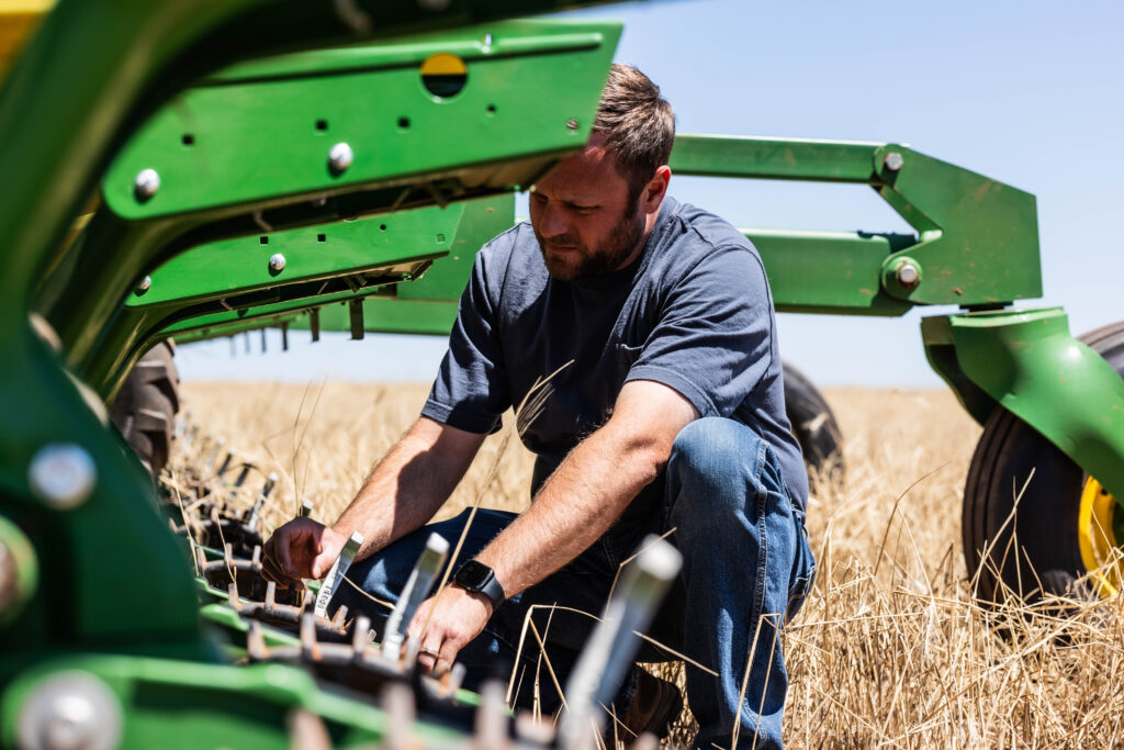 Farmer operating no till farming equipment with no till planter and seeder machine similar to no till seed drill