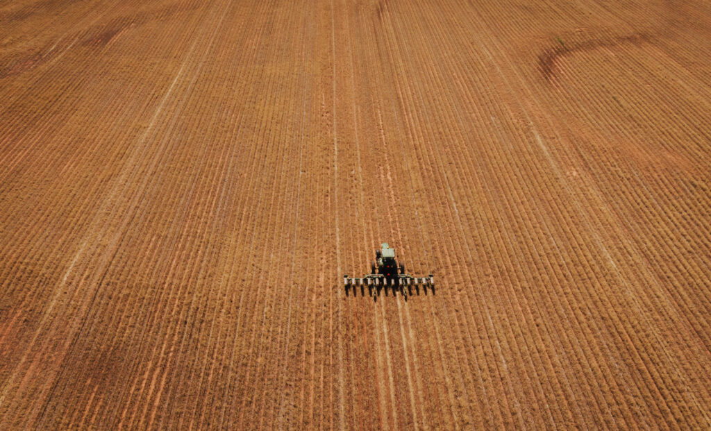 Aerial view of no till farming operation with tractor using no till equipment during no till planting for environmentally friendly farming practices