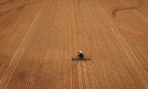 Aerial view of no till farming operation with tractor using no till equipment during no till planting for environmentally friendly farming practices