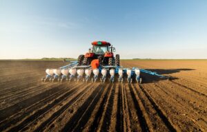 Tractor using cultivator gauge wheels during tillage farming and soil cultivation in a large agricultural field with modern no-till farming equipment.