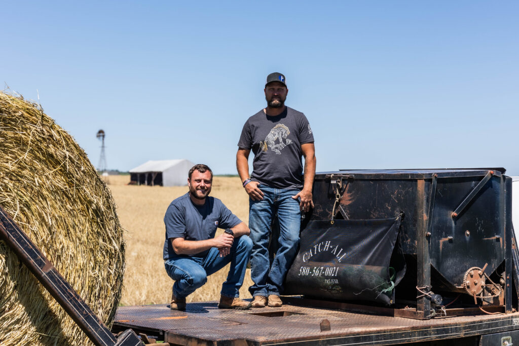 Two ranchers stand beside a feed truck equipped with the Catch-All net sack, one of the most practical ranch clean up tools for storing hay bale netting during daily feeding.